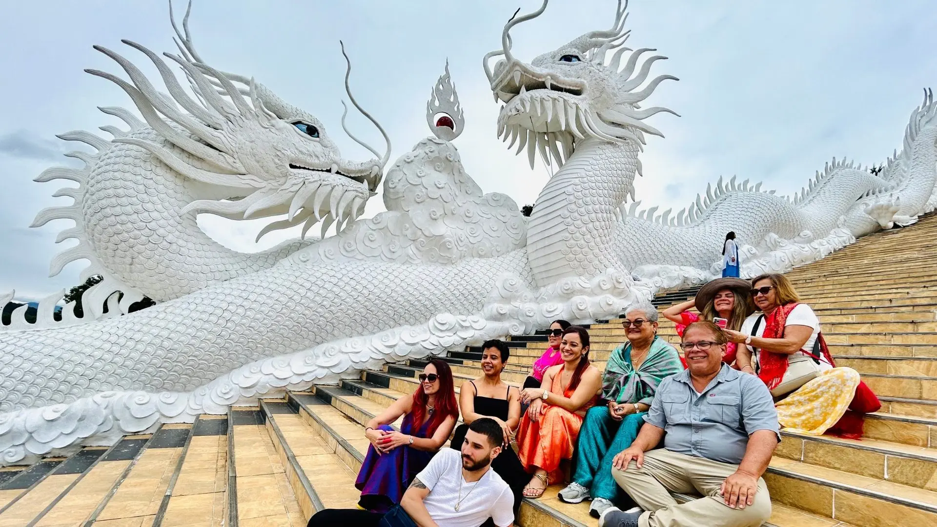 Nine travelers seated on a stairway flanked by two enormous white dragons