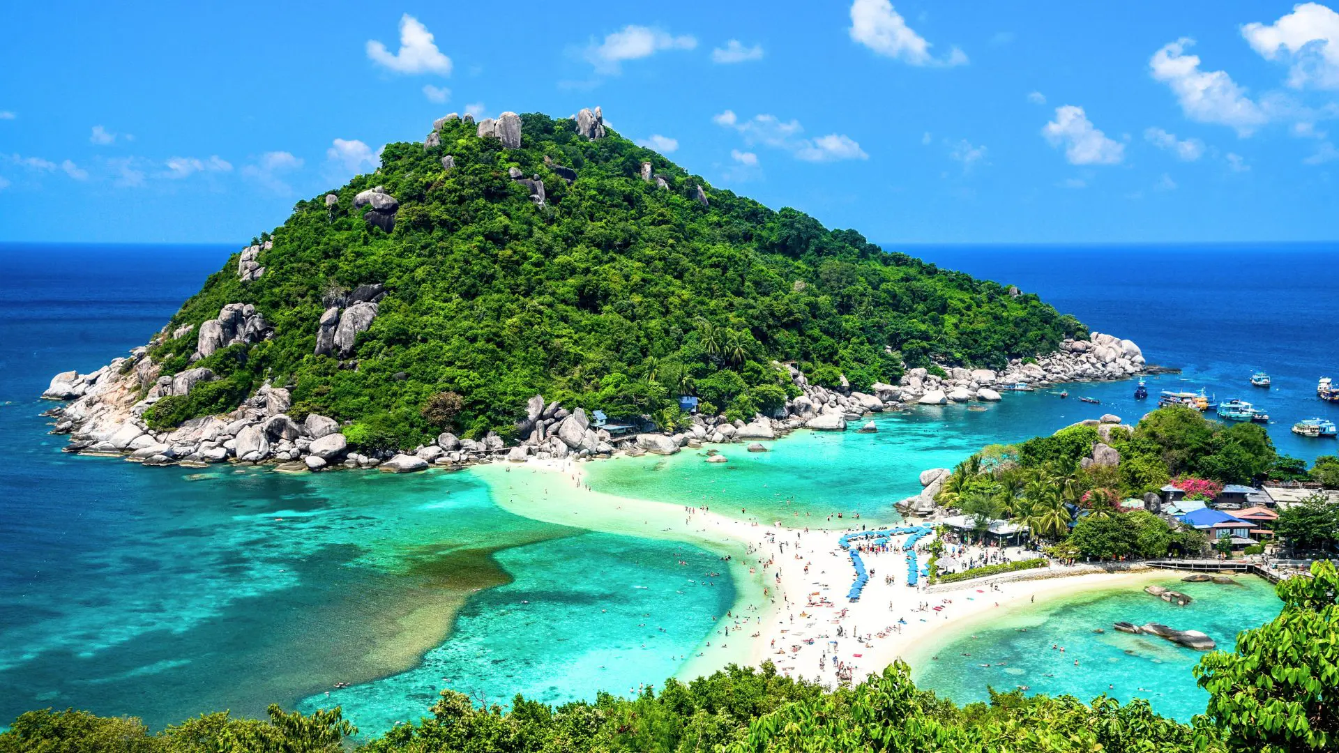 Koh Nang Yuan vista do alto, com a praia de areia cheia de guarda-sóis azuis e um monte coberto de selva