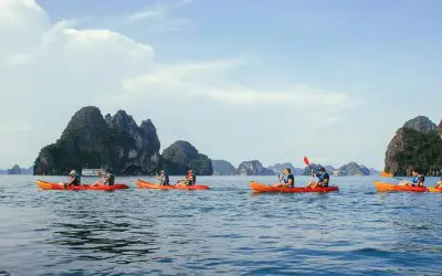 Casais a remar em caiaques cor de laranja em frente a ilhéus escarpados