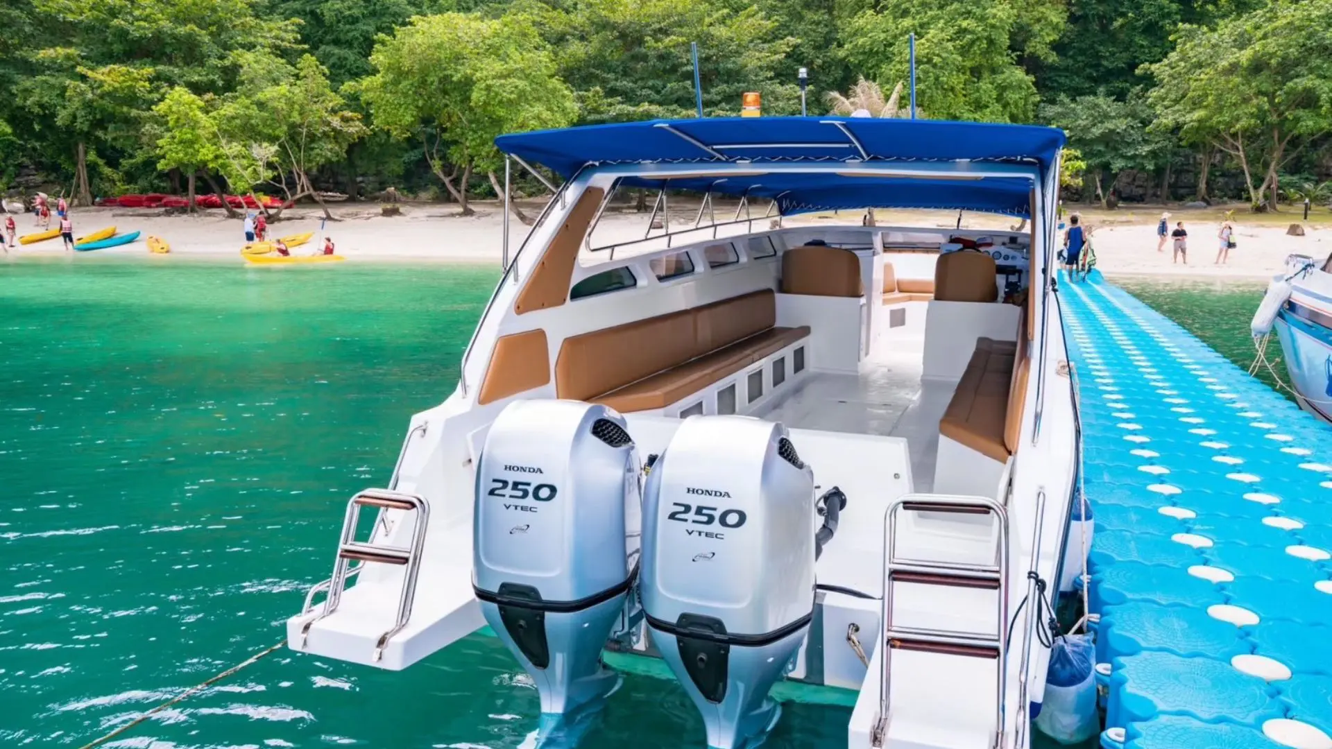Popa de uma lancha rápida com dois motores fora de borda, amarrada a um pontão flutuante azul junto à praia