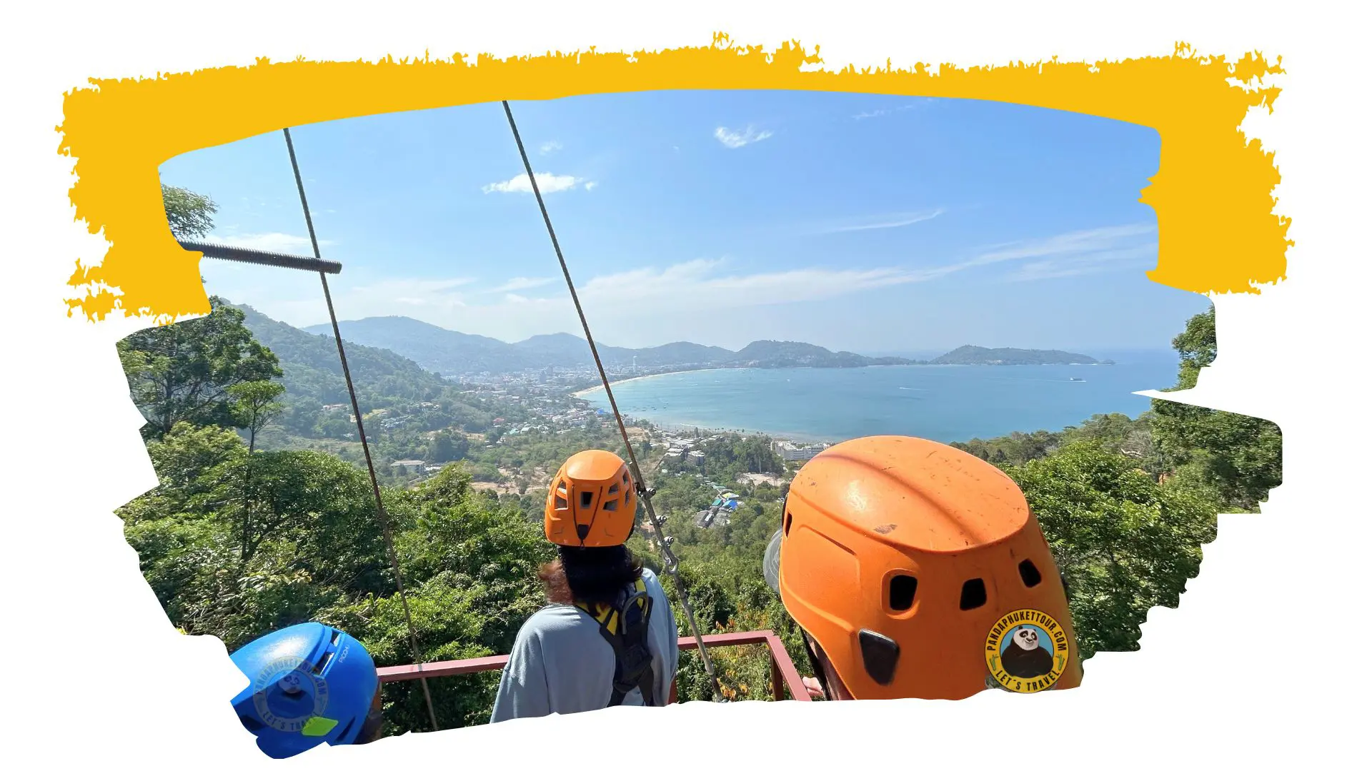 Three people in helmets, two orange and one blue, look out over Patong Bay from the zip line platform
