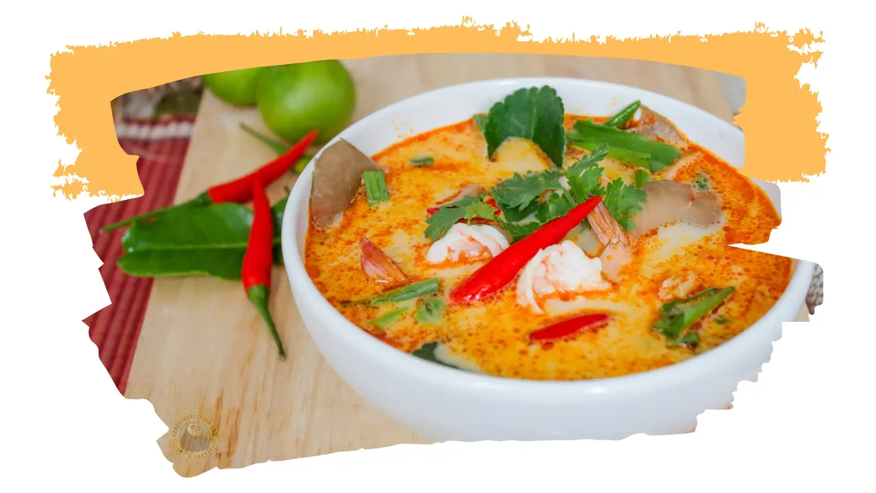 Bowl of spicy Thai soup with shrimp, red chilies and cilantro on a wooden board