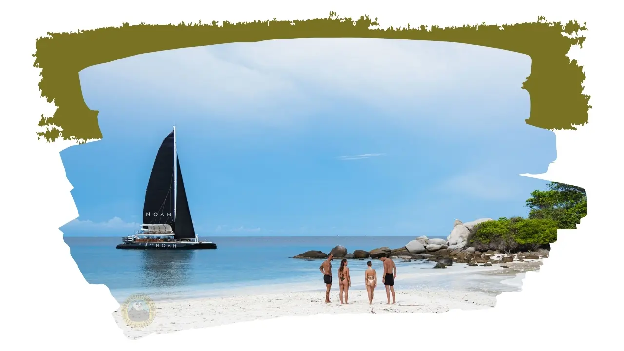 Duas raparigas de biquíni e dois rapazes de calções pretos de pé na areia, com o catamarã de velas pretas no mar calmo