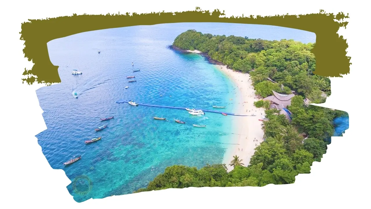 Vista aérea de uma praia em meia-lua rodeada de selva, com barcos de cauda longa e lanchas fundeados na água turquesa